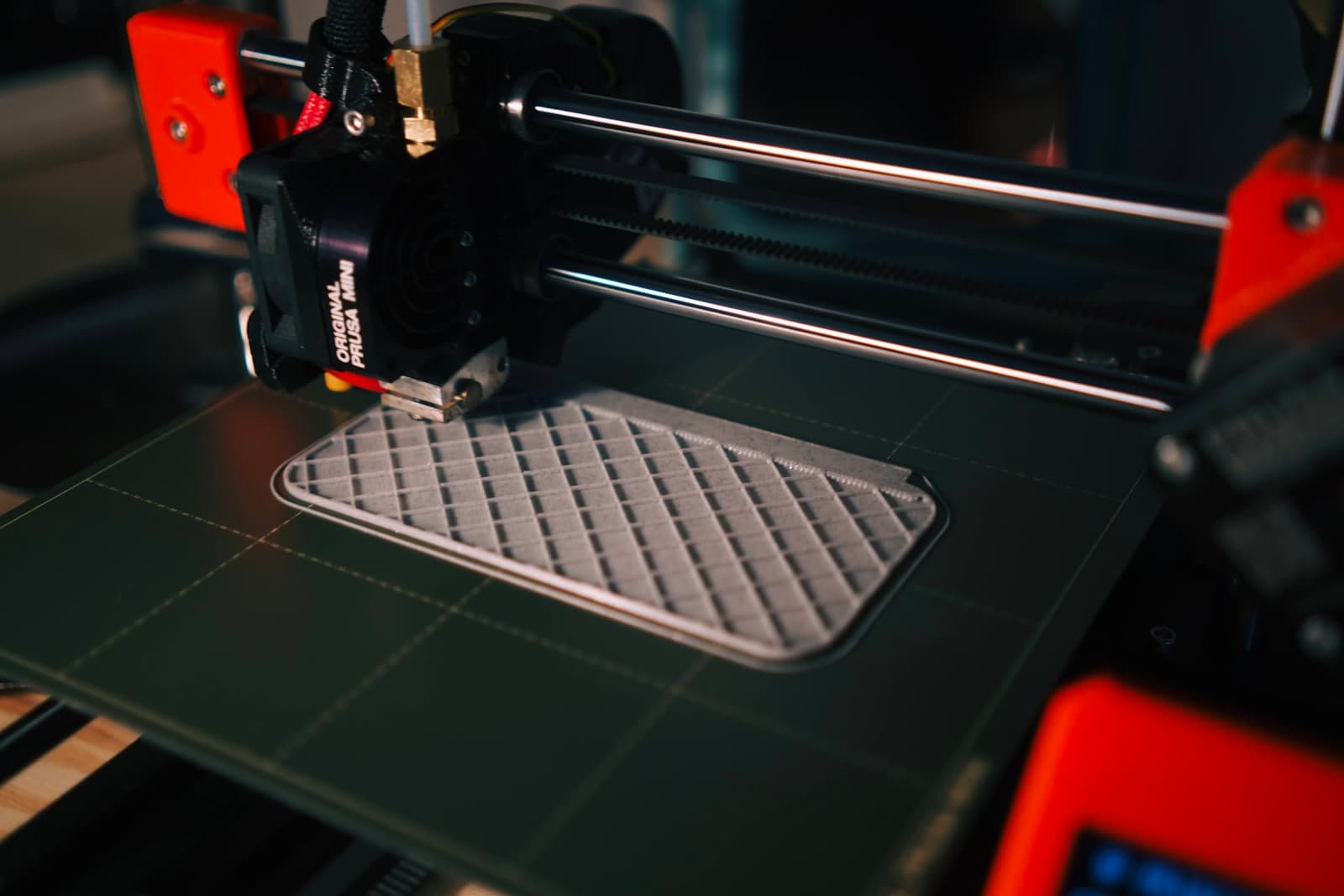 A desktop 3D printer part-way through laying down the infill lattice of a flat component