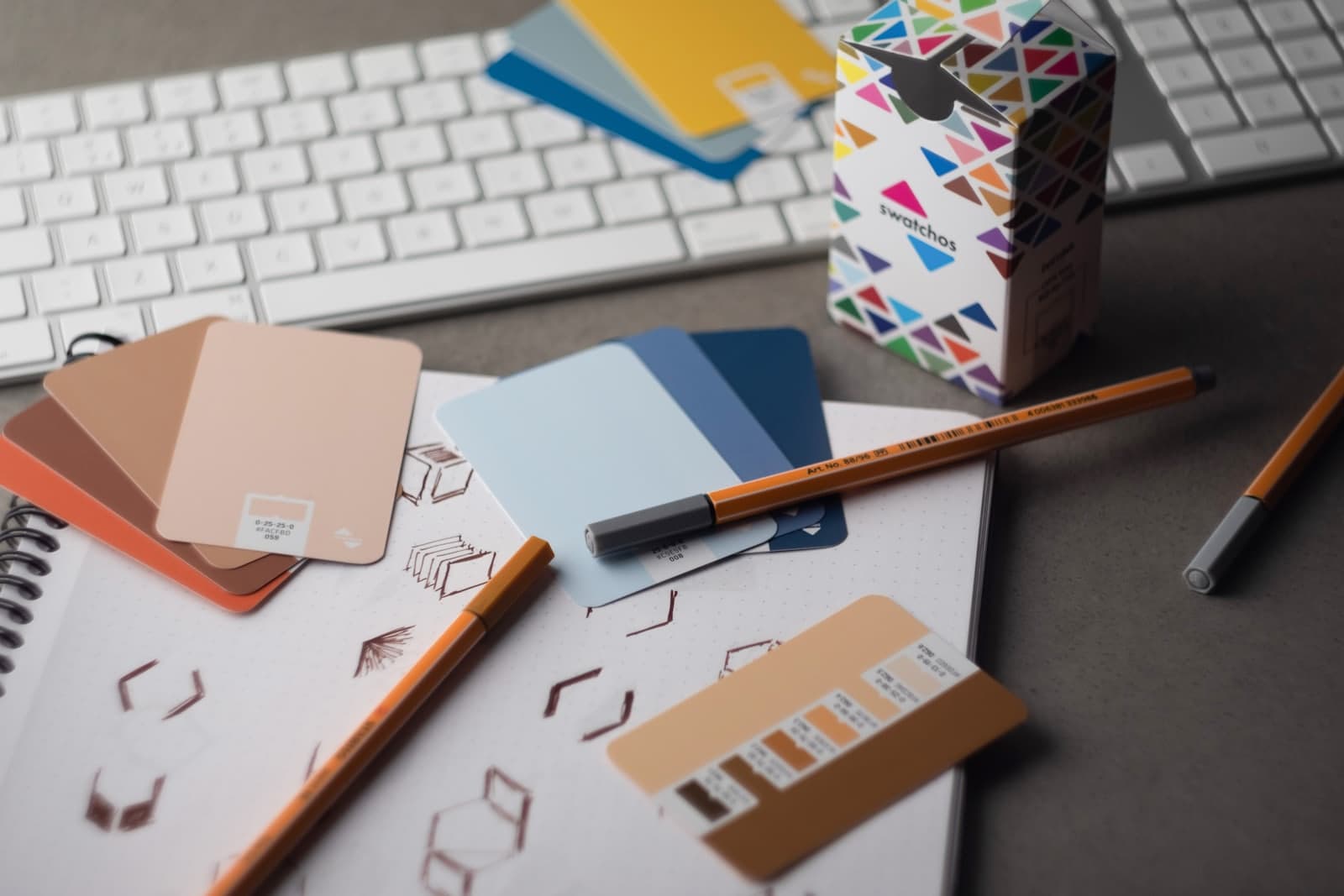 A desk with a keyboard, pencils, and various color samples